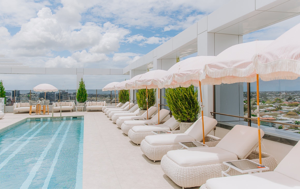a rooftop pool area with large white daybeds